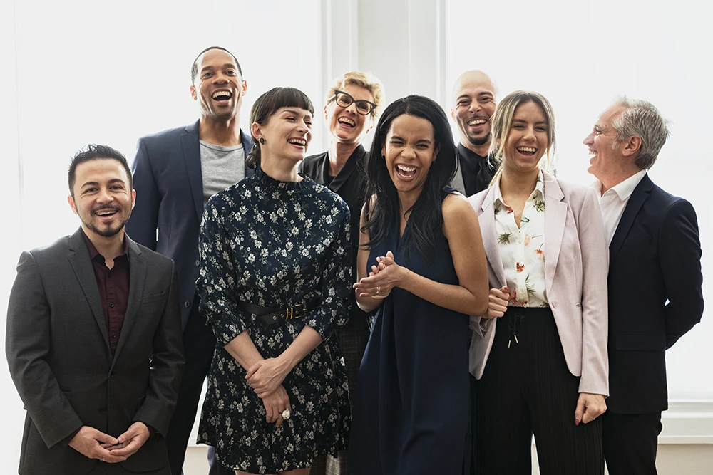 Happy, group of business professionals celebrating together in a bright office environment, representing successful temp-to-hire placements