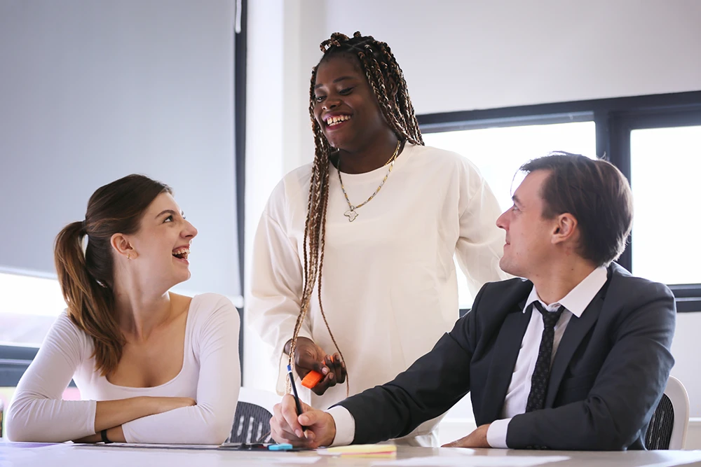 Three business professionals shaking hands and smiling during a successful staffing placement meeting in a Dallas office