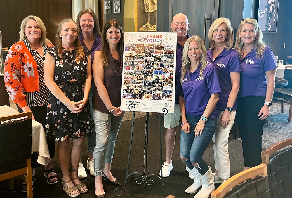 PrideStaff Dallas team and Ally's Wish representatives pose together at their partnership celebration luncheon, standing around a 'Thank You' display board featuring a collage of photos from 25 years of community service. The group of eight women are dressed professionally, with Ally's Wish team members wearing purple branded shirts, gathered in an upscale restaurant setting