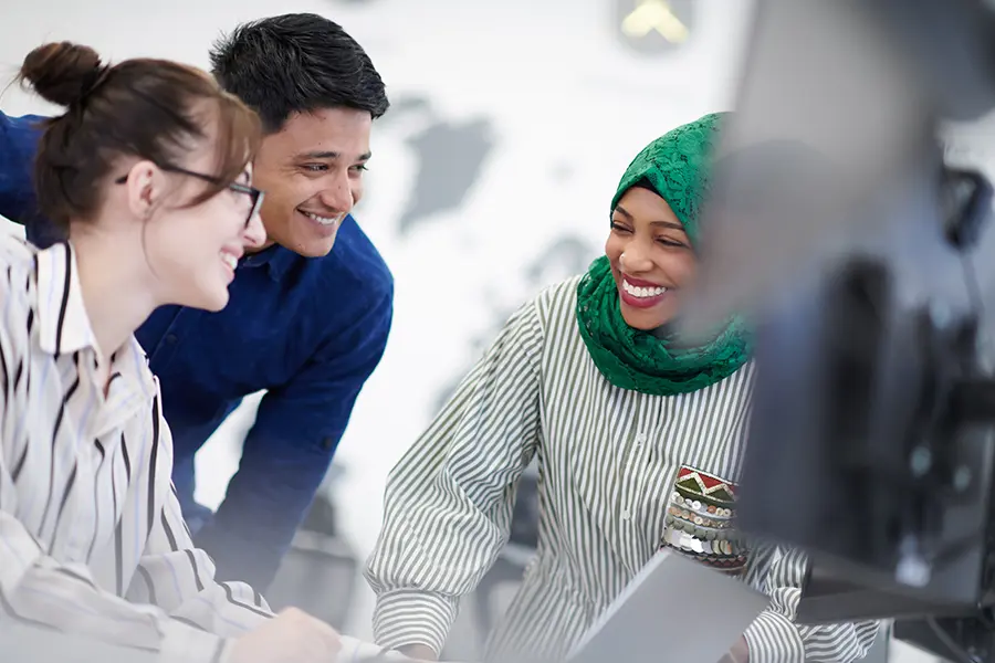 Three professionals collaborating at a computer in a modern Dallas office, representing in-demand workplace skills for 2026 job seekers