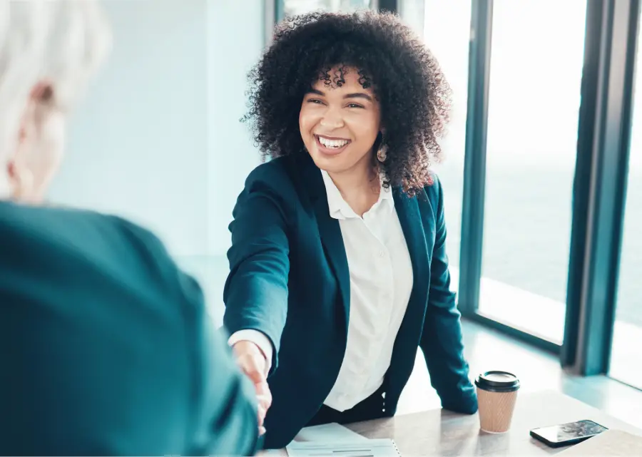 A job seeker shaking hands with a recruiter at a staffing agency meeting in Dallas