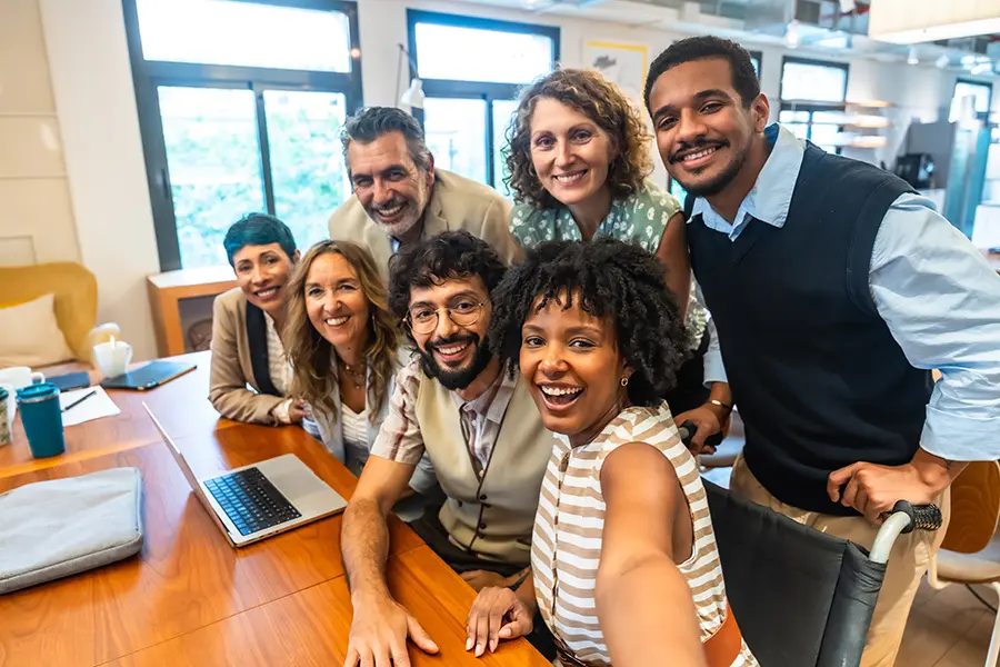 Smiling accounting and finance team gathered around a laptop in a Dallas office